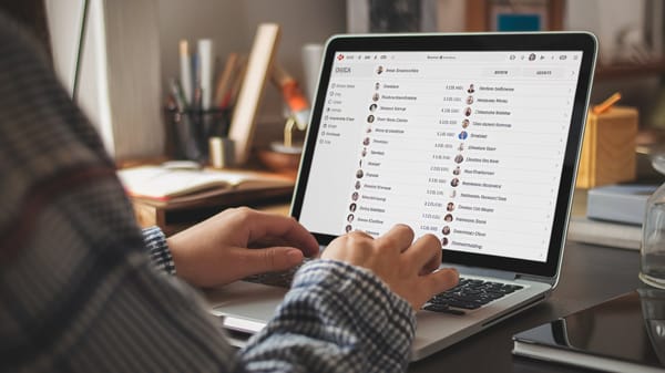 A photo of a person typing on a laptop. The laptop screen shows a list of usernames of facebook.