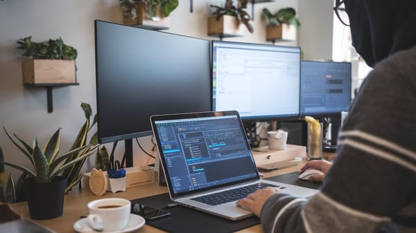 A photo of a person working from a desk with a laptop open.